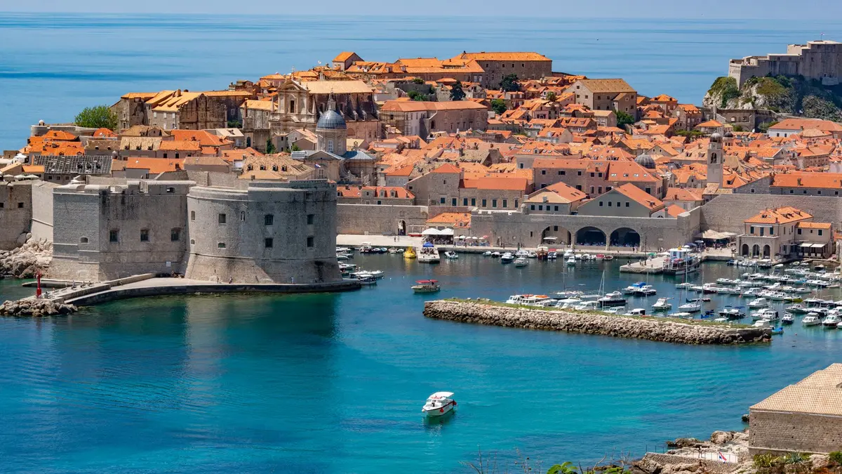 Turquoise Adriatic water surrounding Croatian islands with red-roofed stone villages and pine-covered hillsides