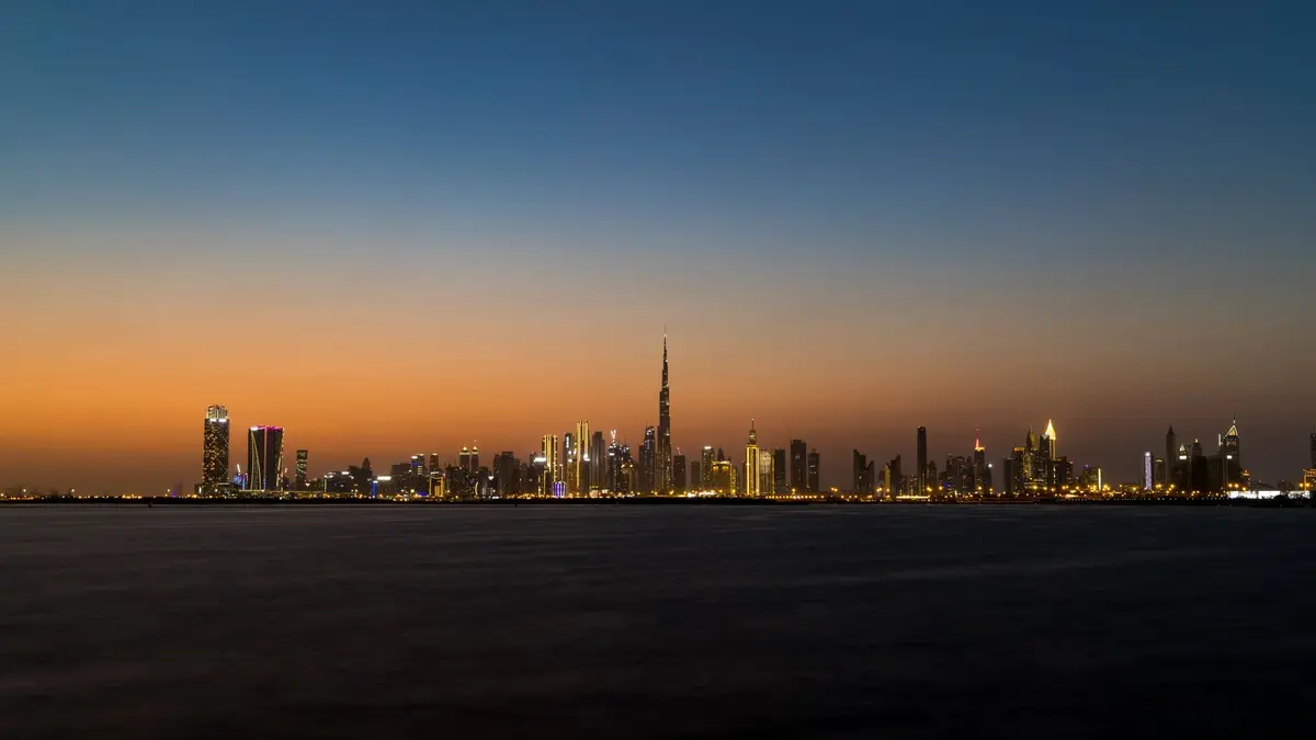 Dubai skyline at sunset with the Burj Khalifa and Dubai Creek in the foreground, golden light reflecting on the water