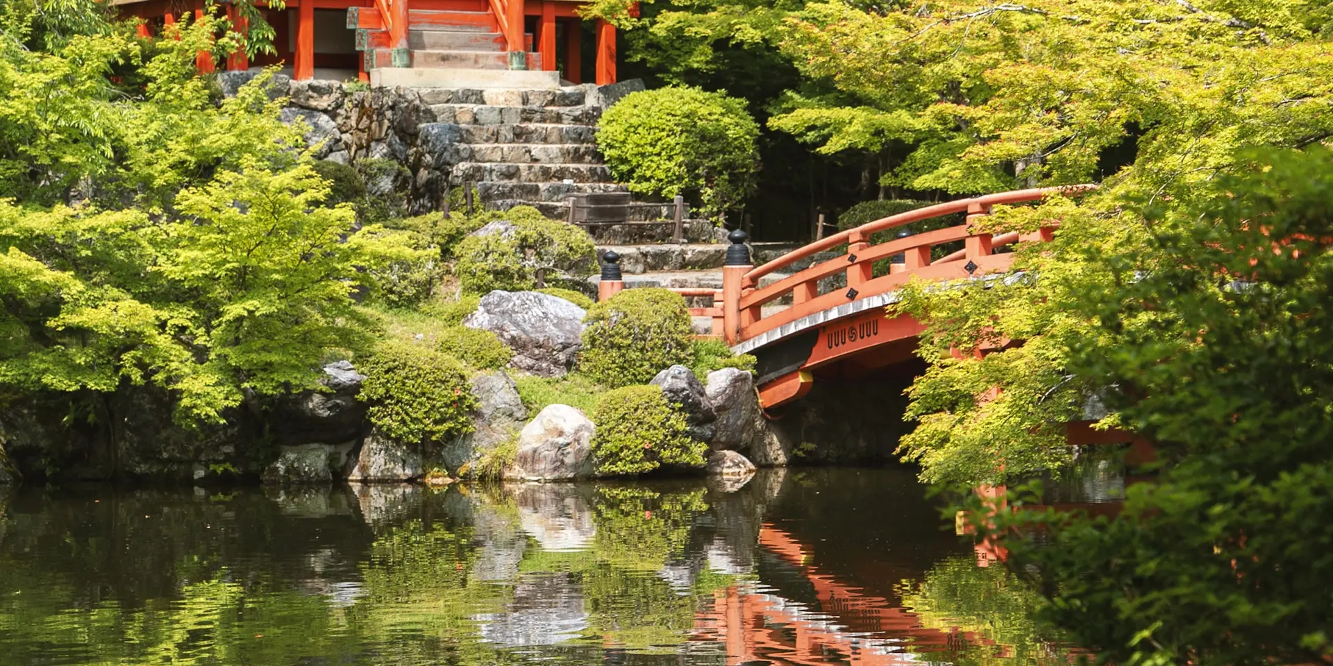 Golden Kinkaku-ji temple reflected in its mirror pond surrounded by Japanese maple trees