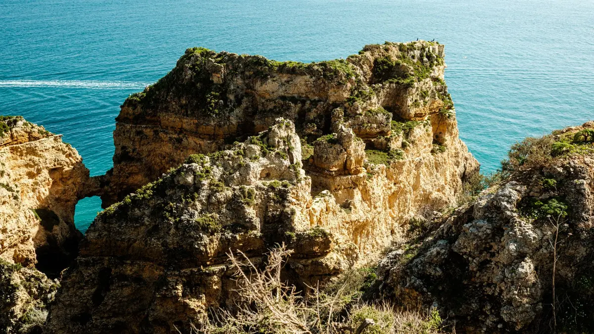 Winding coastal road along the Algarve cliffs in Portugal with golden light and turquoise Atlantic water below