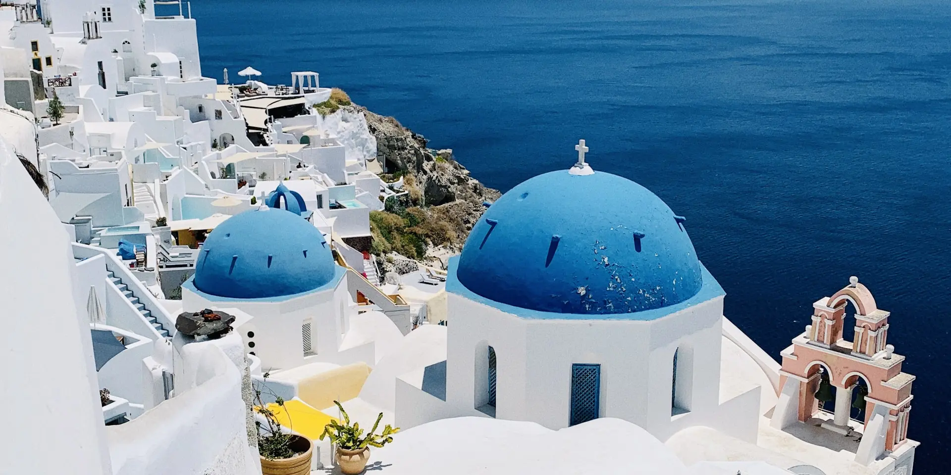 White-washed buildings and blue-domed churches overlooking the Santorini caldera at sunset