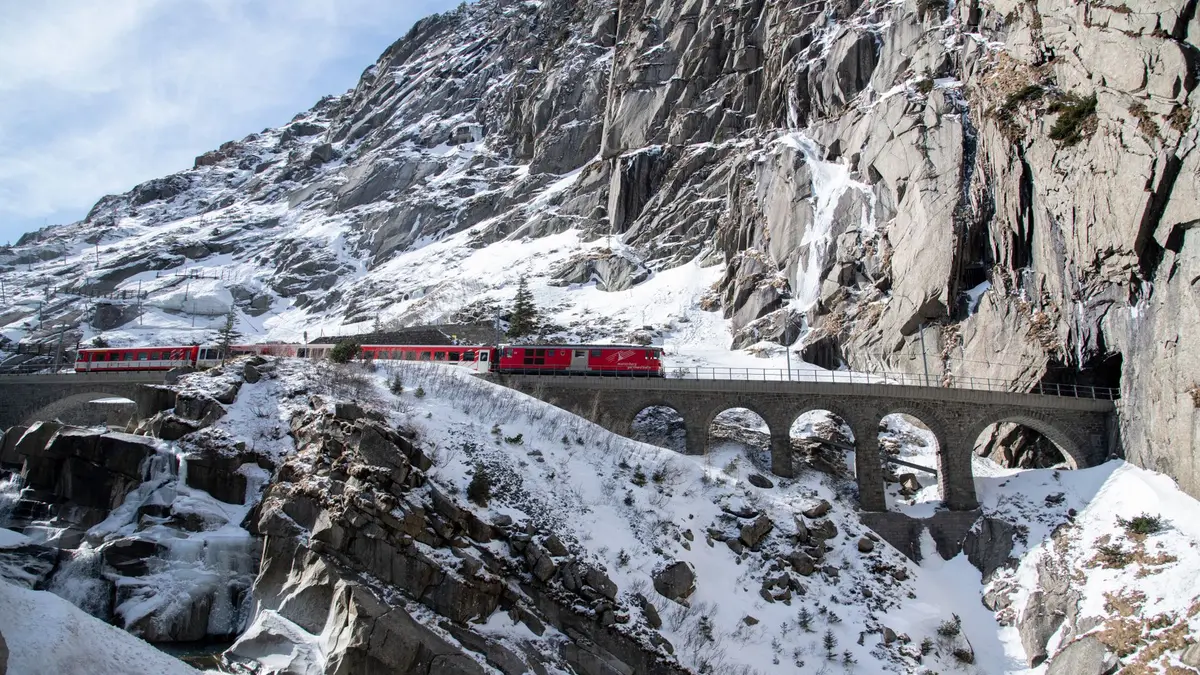 Swiss train crossing a viaduct with snow-capped Alps